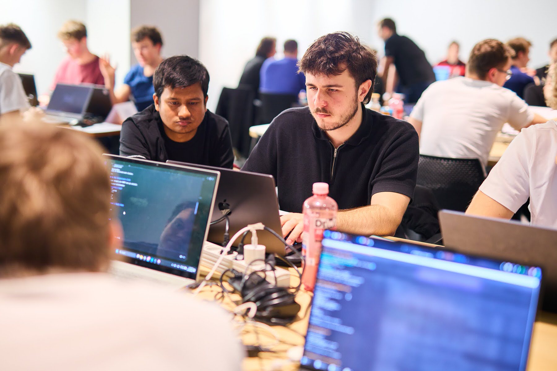 Working at the hackathon, coding on laptops with a teammate